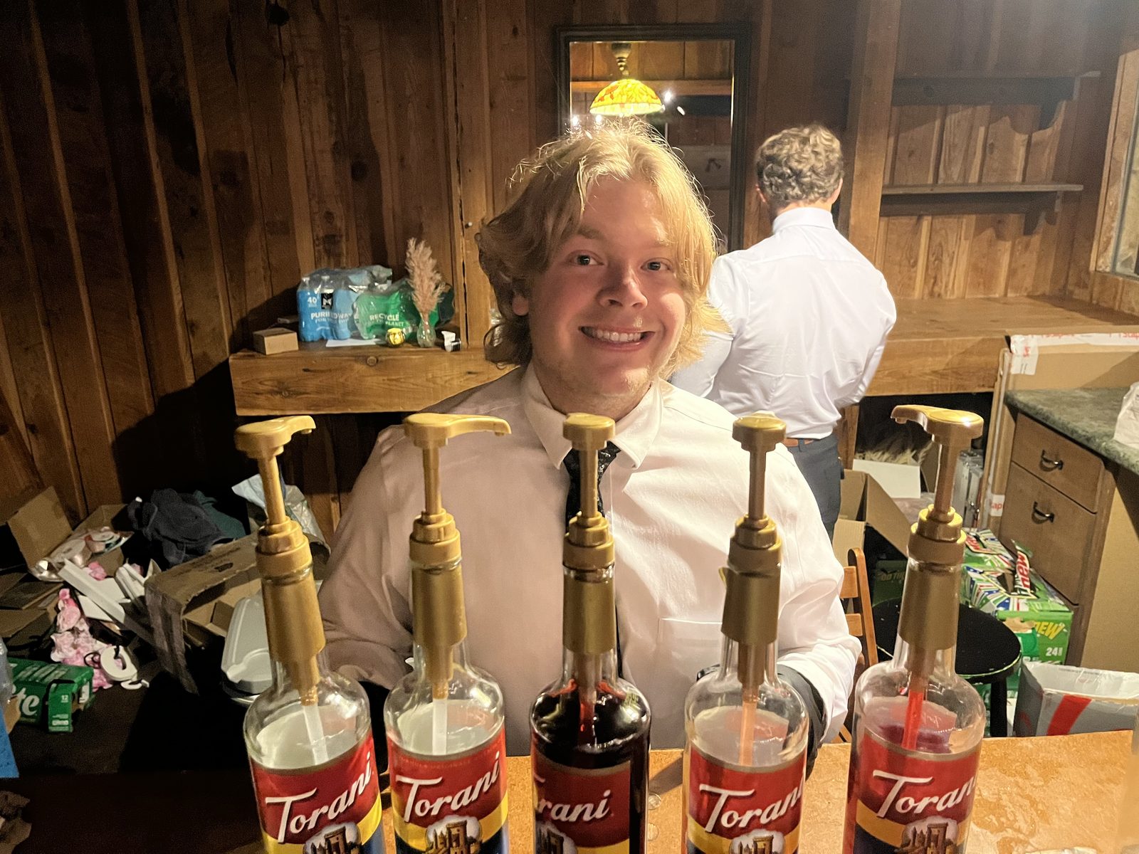 Bartender smiling behind a lineup of Torani syrups